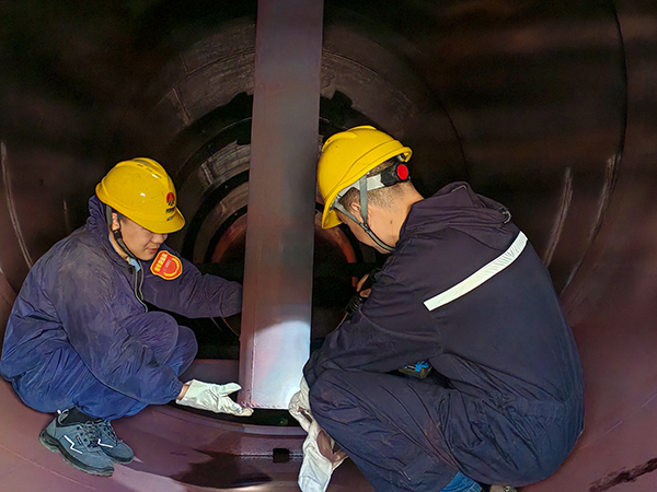 技術員王偉正在給青工岳維哲講解除氧器內部結構.jpg